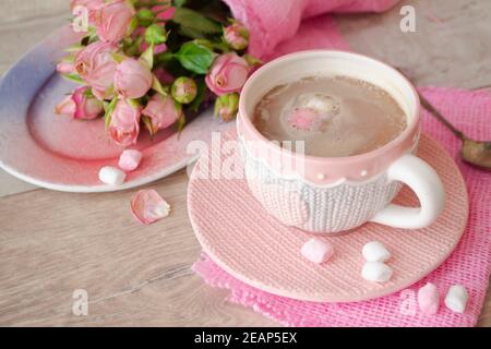 Kakao-Schokoladen-Tasse mit heißem Getränk und weißem und rosa Marshmallow, Kakao in Tasse mit rosa Rosen, Urlaub Coffee House Shop, romantische Dekoration, Tasse mit gestrickten Effekt Stockfoto