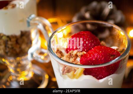 Gesundes mehrlagiges Dessert mit Sahne, Müsli und frischer Erdbeere auf Urlaubshintergrund Stockfoto