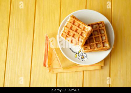 Zwei leckere Waffeln auf gelbem und orangefarbenem Hintergrund von oben Stockfoto