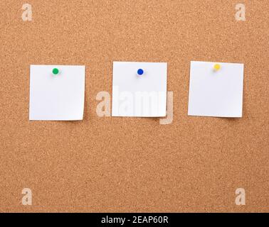Weiße quadratische leere Papierstücke, die auf einem Korken fixiert sind Platine Stockfoto