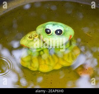 Statue eines Spielzeugfrosches mit einem Frosch unter Wasser in einem Teich. Stockfoto