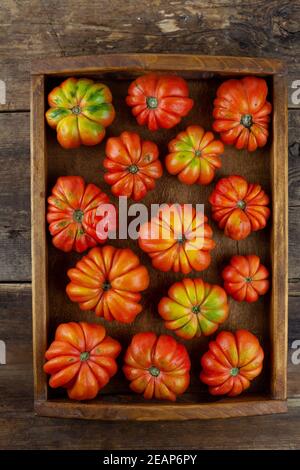 Rote gerippte Tomaten auf einem Holzhintergrund. Amerikanische oder Florentiner Sorte Nina . Tomate Blick von oben. Essen auf dem Tisch. Ort für Ihren Text. Herbstharv Stockfoto