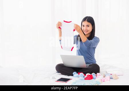 Mutter online einkaufen für ihr Baby Kleidung auf Laptop-Computer Stockfoto