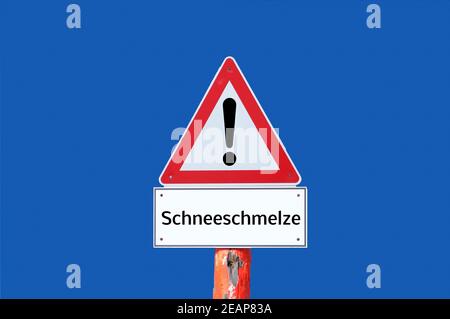 Vorsicht Schmelzende Schnee Warnschild auf blauem Hintergrund in deutsch Stockfoto