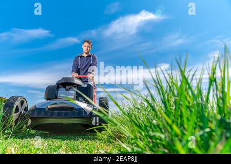 Mann mäht den Rasen mit einem Rasenmäher. Kopierraum Stockfoto