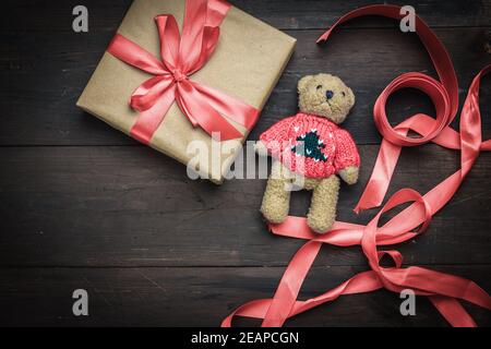 Quadratische Box in braunem Kraftpapier verpackt und gebunden mit Rotes Seidenband Stockfoto