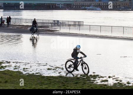 Rheinflut am 4th. Februar 2021 fährt Kind auf dem überfluteten Rheinufer in Deutz, Köln, durch das Wasser. Hochwa Stockfoto