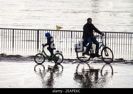 Rheinflut am 4th. Februar 2021 fahren Kinder und Erwachsene auf dem überfluteten Rheinufer in Deutz, Köln, Deutsch, Fahrrad durch das Wasser Stockfoto