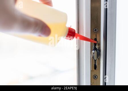 Die Hand schmiert den Fensterrahmen mit Öl Stockfoto