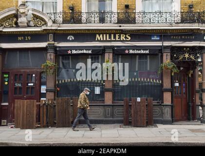 Ein Mann mit einer schützenden Gesichtsmaske geht während der Coronavirus-Sperre an einem geschlossenen Pub im Zentrum Londons vorbei. London, Großbritannien, Februar 2021. Stockfoto
