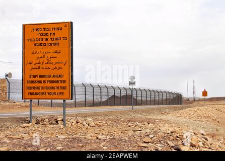 Ein gelbes Warnschild befindet sich neben dem Grenzzaun zwischen Israel und Ägypten entlang des israelischen Highway 12 nördlich von Eilat. Stockfoto