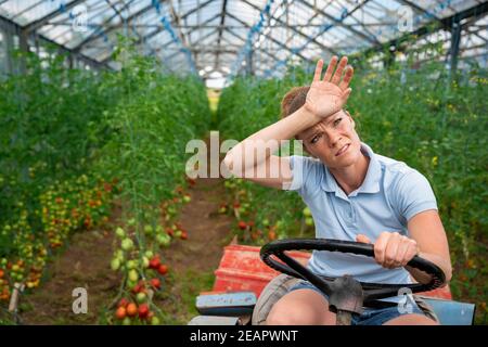 Müde während der Arbeit in einem Gewächshaus auf einem Traktor Stockfoto