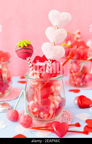 Kleines Glas mit niedlichen herzförmigen Süßigkeiten für Valentinstag Stockfoto