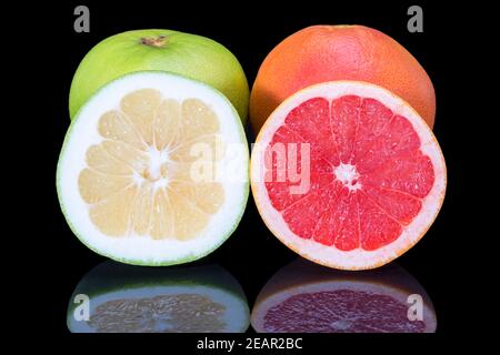 Zitrusfrüchte von roten und grünen Grapefruit ganz und halb Isoliert auf schwarzem Hintergrund Nahaufnahme Stockfoto