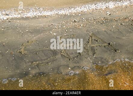 Die Inschrift des Meeres auf dem Sand. Küsten Sand und Wellen. Inschriften am Ufer Stockfoto