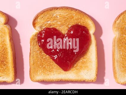 Toast mit herzförmiger Erdbeermarmelade darauf als ein Konzept für Liebe und Valentinstag von oben aufgenommen Stockfoto