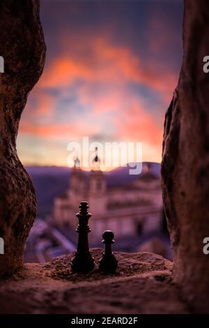 Schwarzer Schachkönig und Pfand auf Steinfenster, die den Sonnenuntergang beobachten Stockfoto
