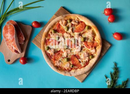 Meeresfrüchte-Pizza mit Lachs und Oliven auf blauem Hintergrund Stockfoto