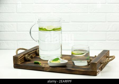 Eine hausgemachte Limonade aus Kalk steht in einem Glas und Krug auf einem Holztablett Stockfoto