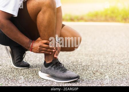 Sport Läufer Mann verwenden Hände Gelenk halten Beinschmerzen, weil Verdrehter Knöchel beim Laufen gebrochen Stockfoto