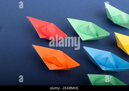 Eine Gruppe von bunten Papierbooten in tiefblau. Konzept der Teamarbeit, Führung Stockfoto