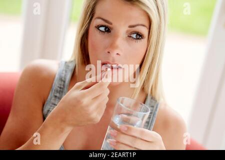 Frau nimmt Tablette mit Glas Wasser Stockfoto