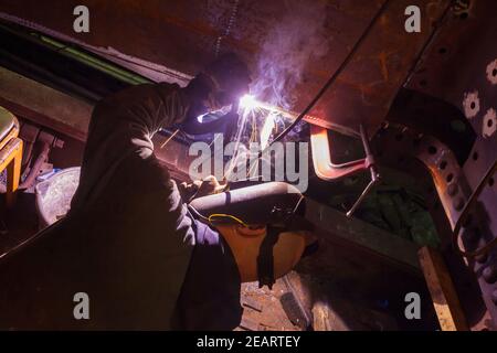 Ein Schweißer arbeitet an der Überholung eines alten Dampfes Lokomotive in der Werkstatt des Keighley und Worth Valley Eisenbahn in Haworth Stockfoto