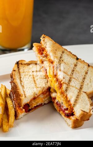 Toast mit Käse, Ei und türkischer Wurst serviert mit Salat und pommes auf weißem Teller Stockfoto