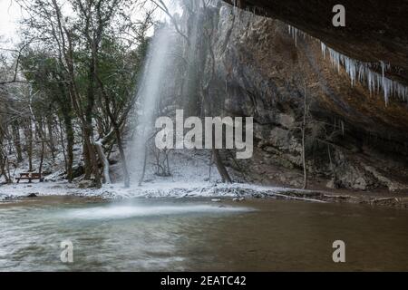 Wasserfall im Winterwald. Schöne Aussicht auf den fallenden reinsten Bergfluss. Eine Felswand mit Eiszapfen, die nach unten hängen. Schneebedeckte Bäume, frisch Stockfoto