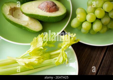 Verschiedene frische grüne Früchte und Gemüse auf grünen Tellern. Das Konzept der gesunden Ernährung. Stockfoto