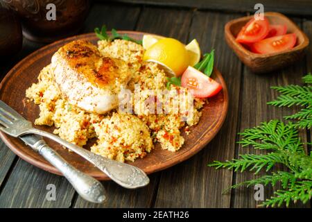 Cous Cous, Huhn und Gemüse auf dunklem Holztisch Stockfoto