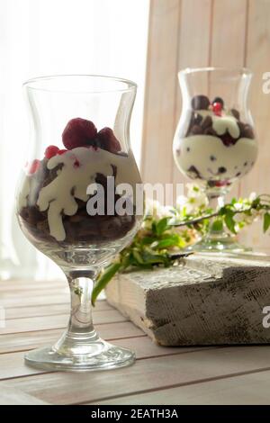 Joghurt mit Schokoladencreme, gehackter Schokolade und Müsli im Glas auf Holztisch serviert Stockfoto