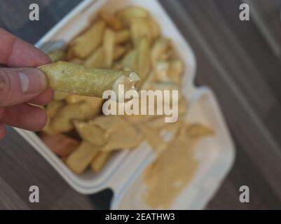 currywurst mit Pommes in eine Tasse. Traditionelle deutsche Küche zum Dip zu Corona Zeiten, konzentrieren sich auf Friese in der Hand Stockfoto