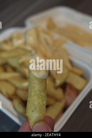 currywurst mit Pommes in eine Tasse. Traditionelle deutsche Küche zum Dip zu Corona Zeiten, konzentrieren sich auf Friese in der Hand Stockfoto