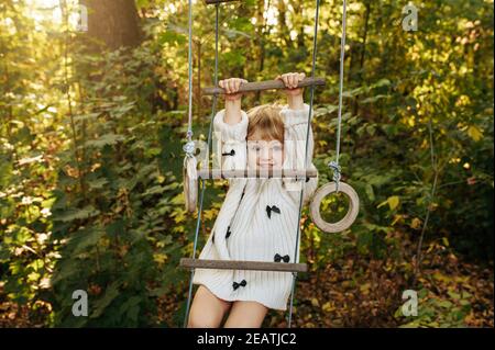 Kleines Mädchen klettert mit einer Seilleiter im Garten Stockfoto