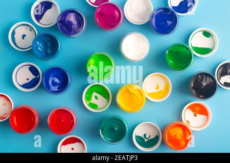 Auf dem Tisch sind Acrylfarben verschiedener Farben zum Zeichnen geöffnet. Helle bunte Hintergrund aus Farbdosen Stockfoto