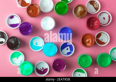 Auf dem Tisch sind Acrylfarben verschiedener Farben zum Zeichnen geöffnet. Helle bunte Hintergrund aus Farbdosen Stockfoto
