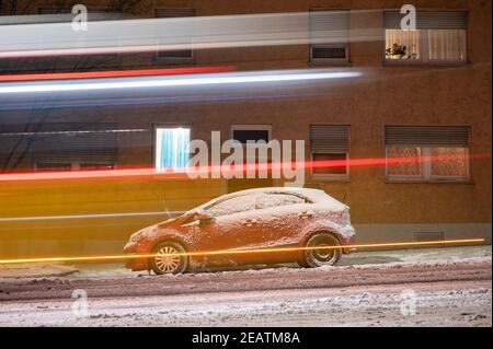 Stuttgart, Deutschland. Februar 2021, 10th. Ein Bus fährt an einem schneebedeckten Auto vorbei. Quelle: Sebastian Gollnow/dpa/Alamy Live News Stockfoto