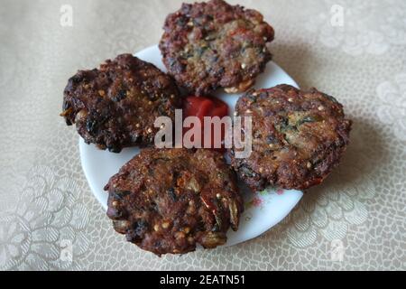 Köstlich würzig gebratener runder Kebab in weißer Keramikplatte mit roter Sauce serviert. Stockfoto