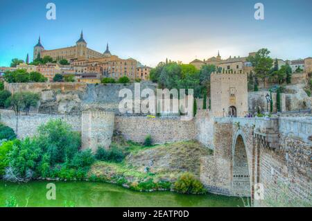 Sonnenuntergang Ansicht der Alcantara Brücke über dem Fluss Tajo mit Alcazar Burg im Hintergrund bei Toledo, Spanien Stockfoto