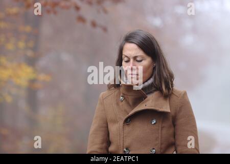 Traurige Frau, die im Winter alleine in einem Park läuft Stockfoto