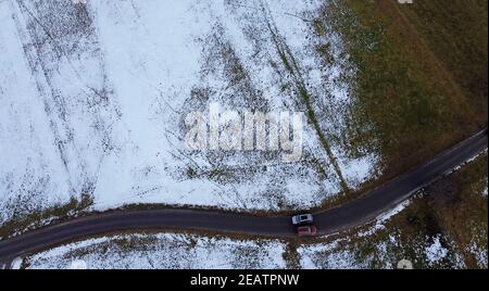 Drohnenfoto von zwei Autos, die im Winter aneinander vorbeifahren Auf schmaler Straße Stockfoto