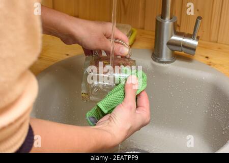 Das Mädchen wäscht das Geschirr gründlich mit einem Lappen Stockfoto