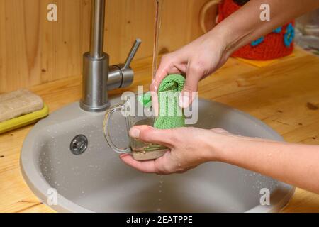 Mädchen wäscht einen Glas Becher unter fließendem Wasser Stockfoto