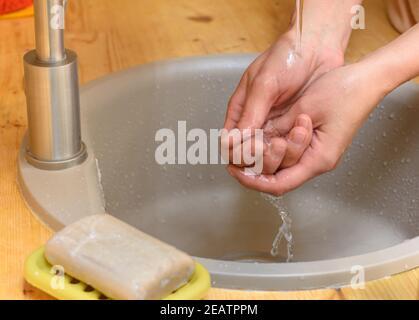 Die Hände des Mädchens waschen ihre Hände im Waschbecken, Seife ist im Vordergrund Stockfoto