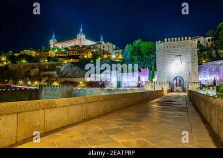Nachtansicht der Alcantara Brücke über den Fluss Tajo mit Alcazar Burg im Hintergrund bei Toledo, Spanien Stockfoto