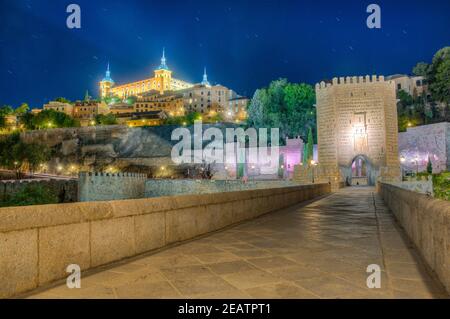 Nachtansicht der Alcantara Brücke über den Fluss Tajo mit Alcazar Burg im Hintergrund bei Toledo, Spanien Stockfoto