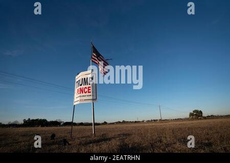 Ein Landwirt außerhalb von Smithville im Bastrop County, TX, fliegt drei Monate nach der Novemberwahl, bei der die republikanische Karte verloren hat, eine leicht zerfetzte amerikanische Flagge über einem Trump-Pence-Wahlkampfschild. Meinungsumfragen zeigen, dass sich viele Texaner im ländlichen Raum immer noch weigern, einen demokratischen Präsidentschaftssieg zu akzeptieren. ©Bob Daemmrich Stockfoto