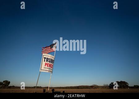 Ein Landwirt außerhalb von Smithville im Bastrop County, TX, fliegt drei Monate nach der Novemberwahl, bei der die republikanische Karte verloren hat, eine leicht zerfetzte amerikanische Flagge über einem Trump-Pence-Wahlkampfschild. Meinungsumfragen zeigen, dass sich viele Texaner im ländlichen Raum immer noch weigern, einen demokratischen Präsidentschaftssieg zu akzeptieren. ©Bob Daemmrich Stockfoto