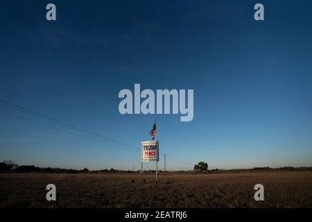 Ein Landwirt außerhalb von Smithville im Bastrop County, TX, fliegt drei Monate nach der Novemberwahl, bei der die republikanische Karte verloren hat, eine leicht zerfetzte amerikanische Flagge über einem Trump-Pence-Wahlkampfschild. Meinungsumfragen zeigen, dass sich viele Texaner im ländlichen Raum immer noch weigern, einen demokratischen Präsidentschaftssieg zu akzeptieren. ©Bob Daemmrich Stockfoto